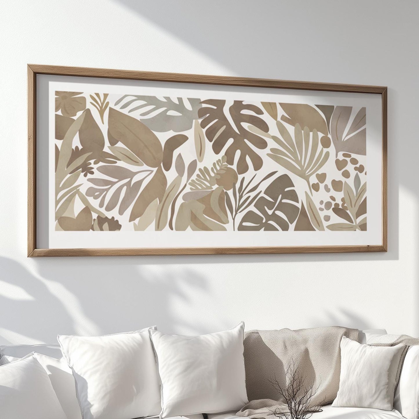 Framed abstract tropical leaf print displayed above a white sofa with cushions
