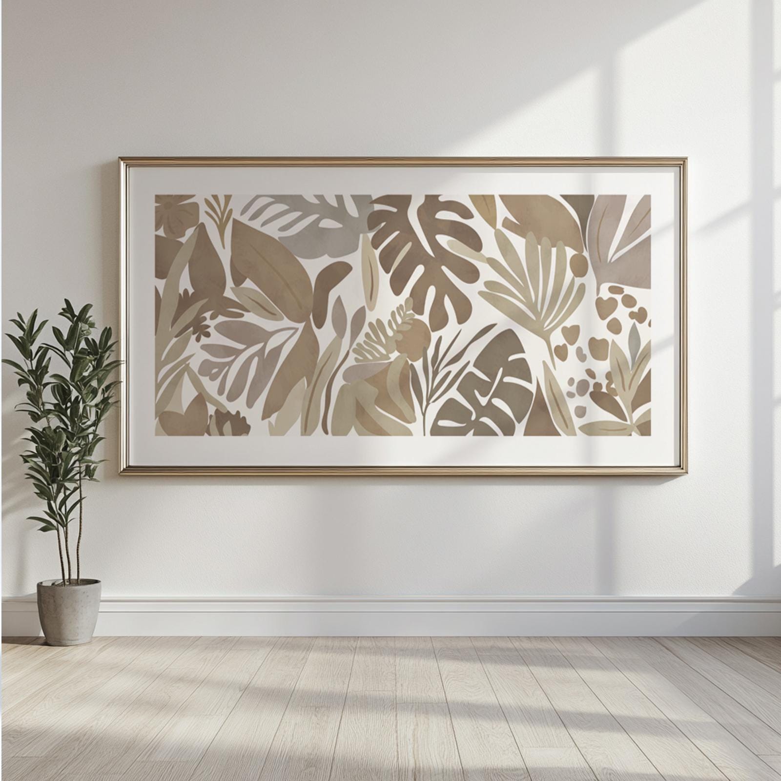 Framed abstract tropical leaves artwork in neutral tones centered on a sunlit wall