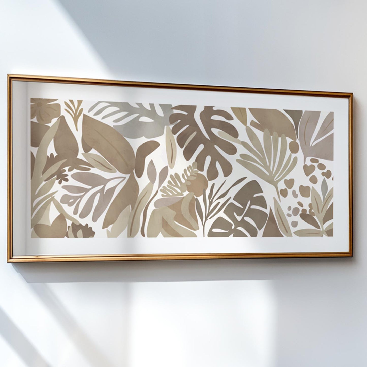 Tropical botanical artwork in soft beige tones, framed in gold and hung on a white wall