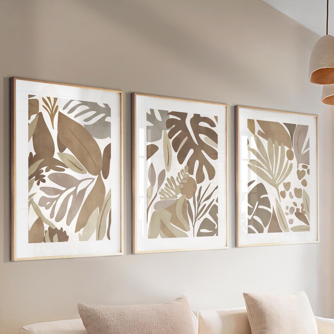 Trio of framed abstract tropical leaf prints in mocha tones above a neutral console
