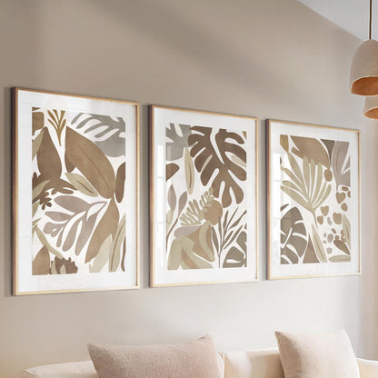 Trio of framed abstract tropical leaf prints in mocha tones above a neutral console