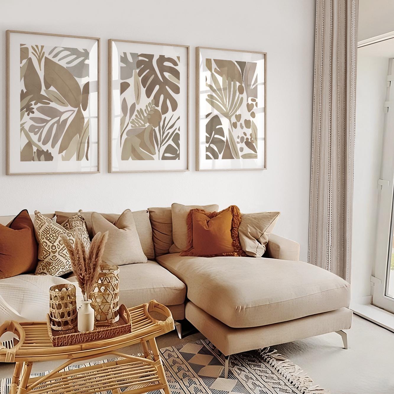 Three framed abstract tropical prints in mocha tones hung above a neutral sectional sofa