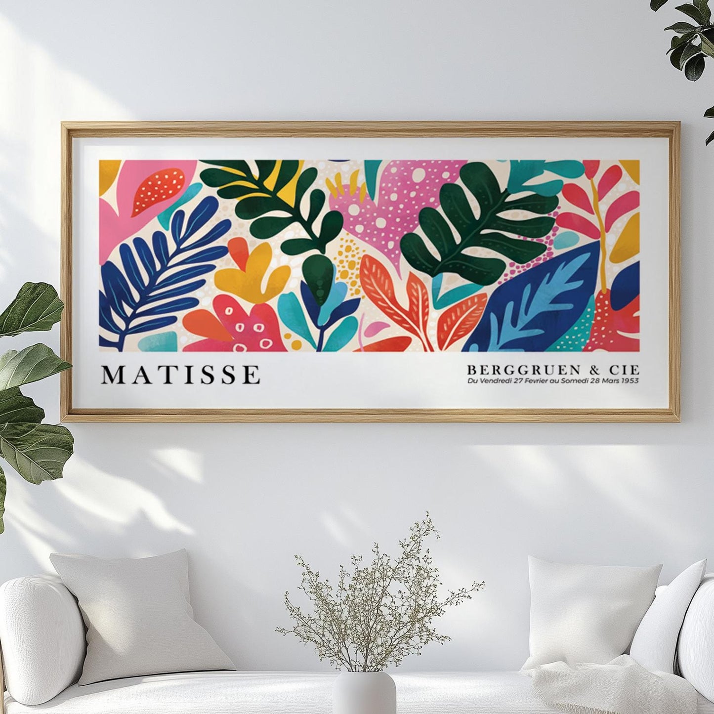 Colorful abstract leaf print in a light wood frame centered above a modern white sofa