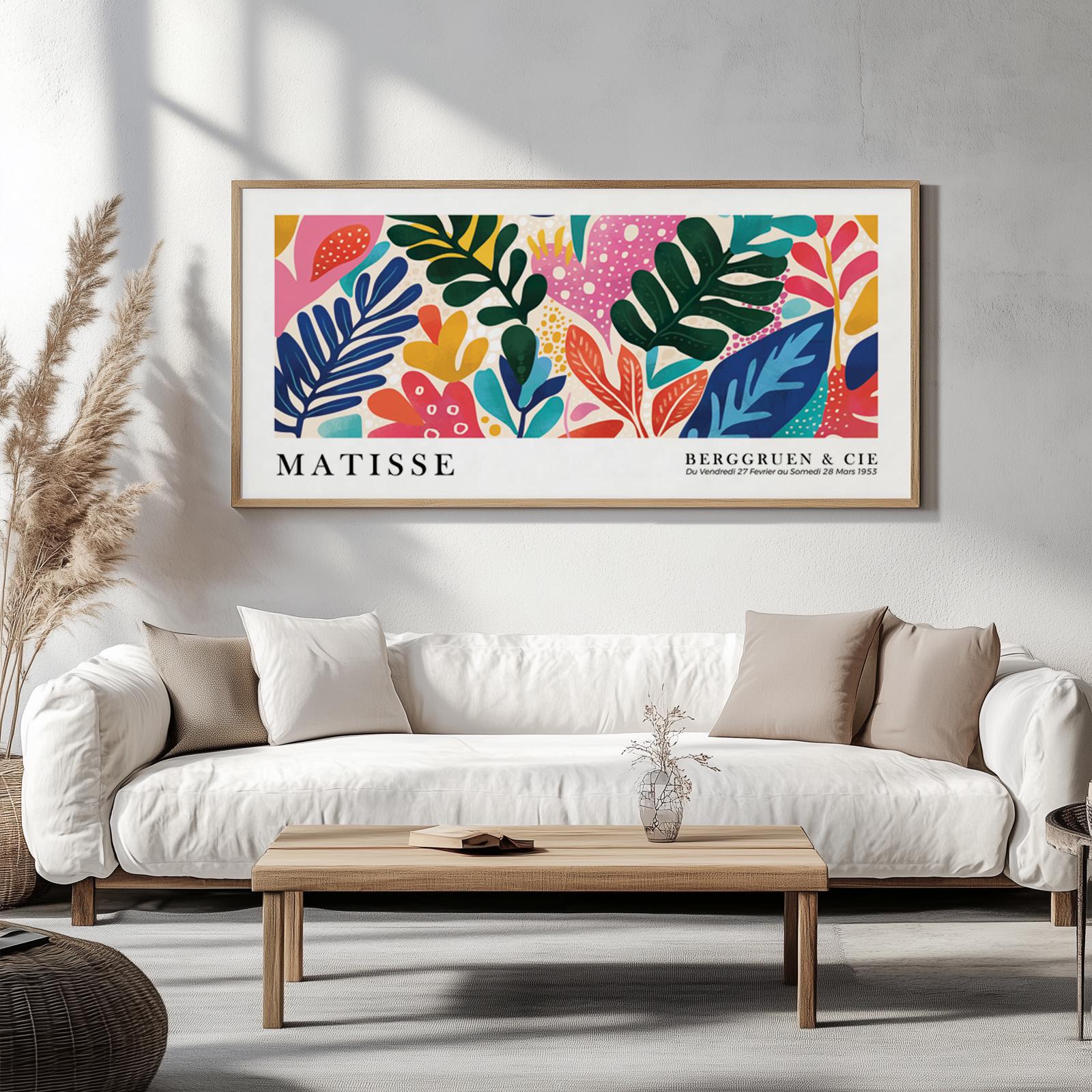 Framed Matisse-inspired print with colorful tropical leaves displayed above a white sofa in sunlit room.