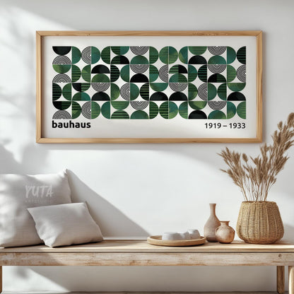 Geometric Bauhaus-inspired print with green and black shapes in a natural wood frame above a console.