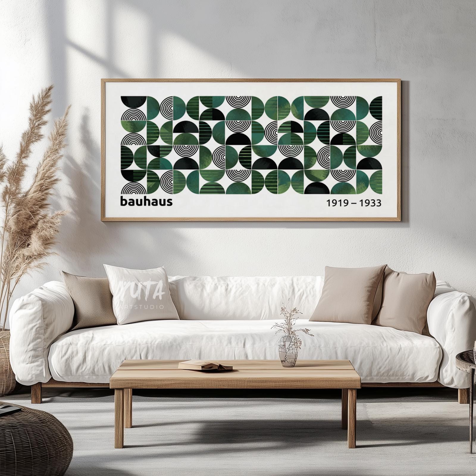 Geometric Bauhaus-inspired print with green and black shapes, framed above a white sofa in soft daylight