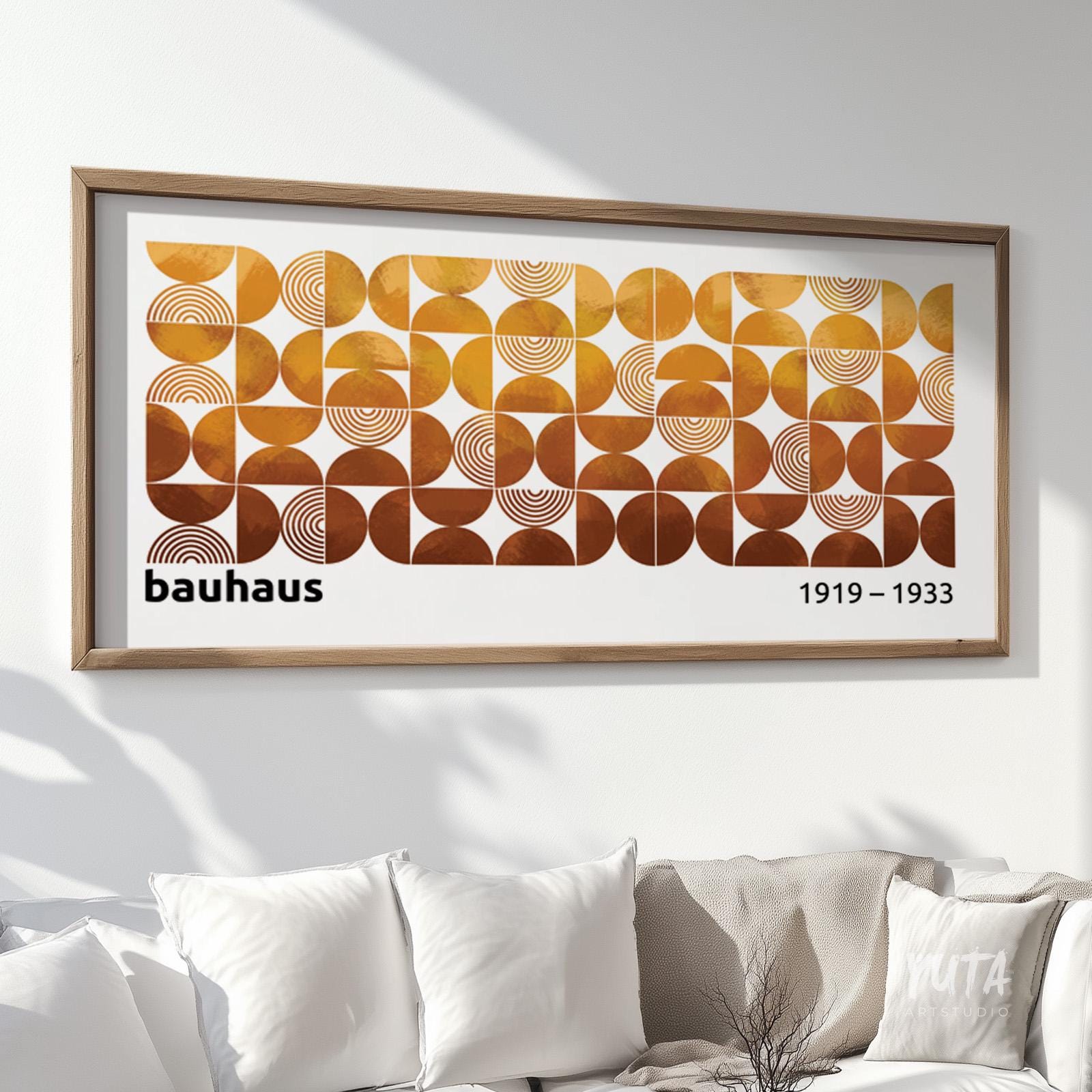 Geometric Bauhaus-style wall art in earth tones framed above a white sofa.