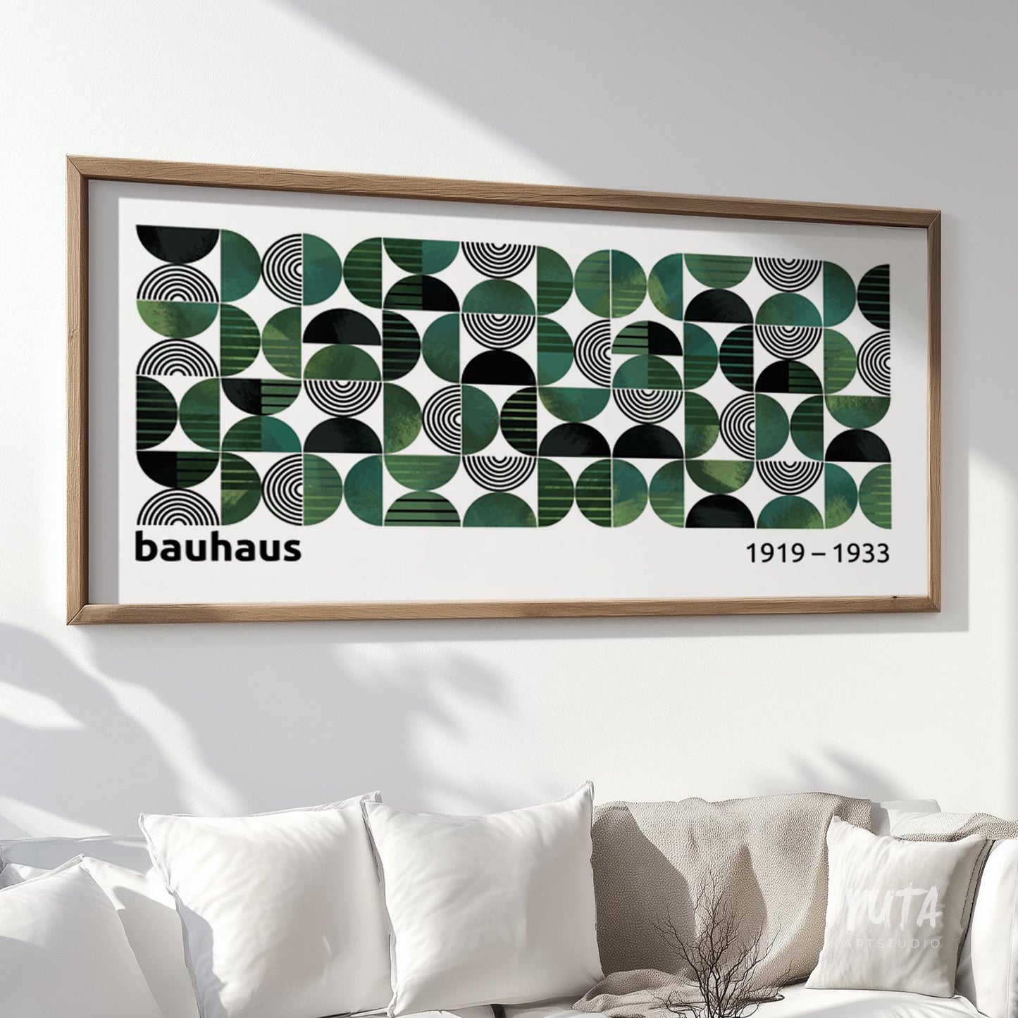 Geometric Bauhaus-style print in green and black, framed in light wood above a sofa