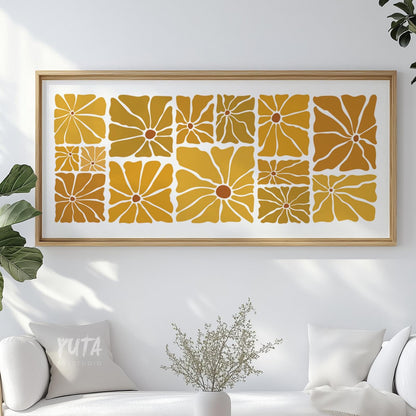 Framed retro floral print in mustard and ochre displayed above a white sofa.