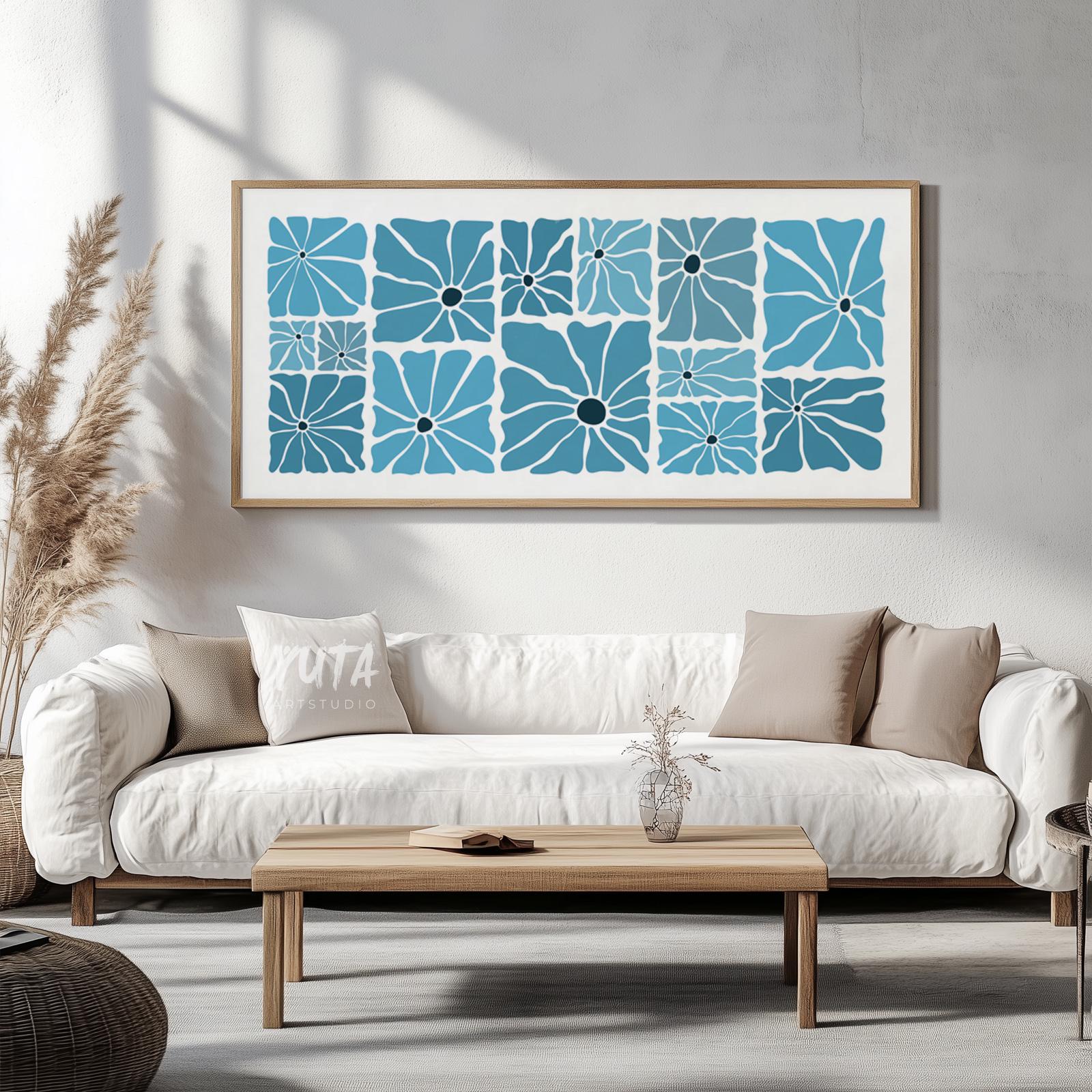 Abstract blue floral artwork in a natural wood frame centered above a white sofa.