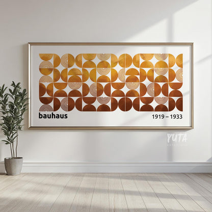Framed geometric Bauhaus wall art in earth tones, hung above wood flooring with soft light.