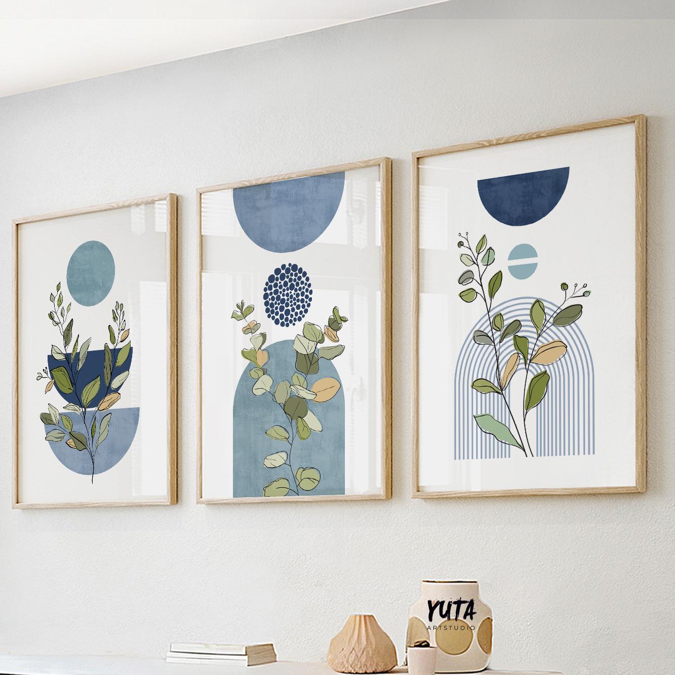 Trio of framed blue botanical prints with geometric shapes in sunlight above a sideboard