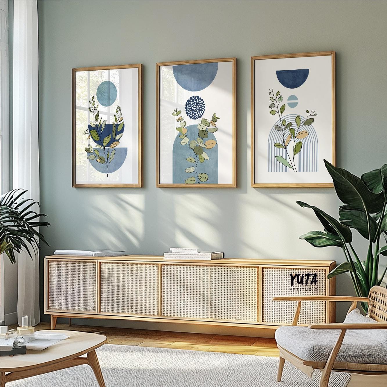 Trio of framed blue botanical geometric prints styled above a natural wood sideboard