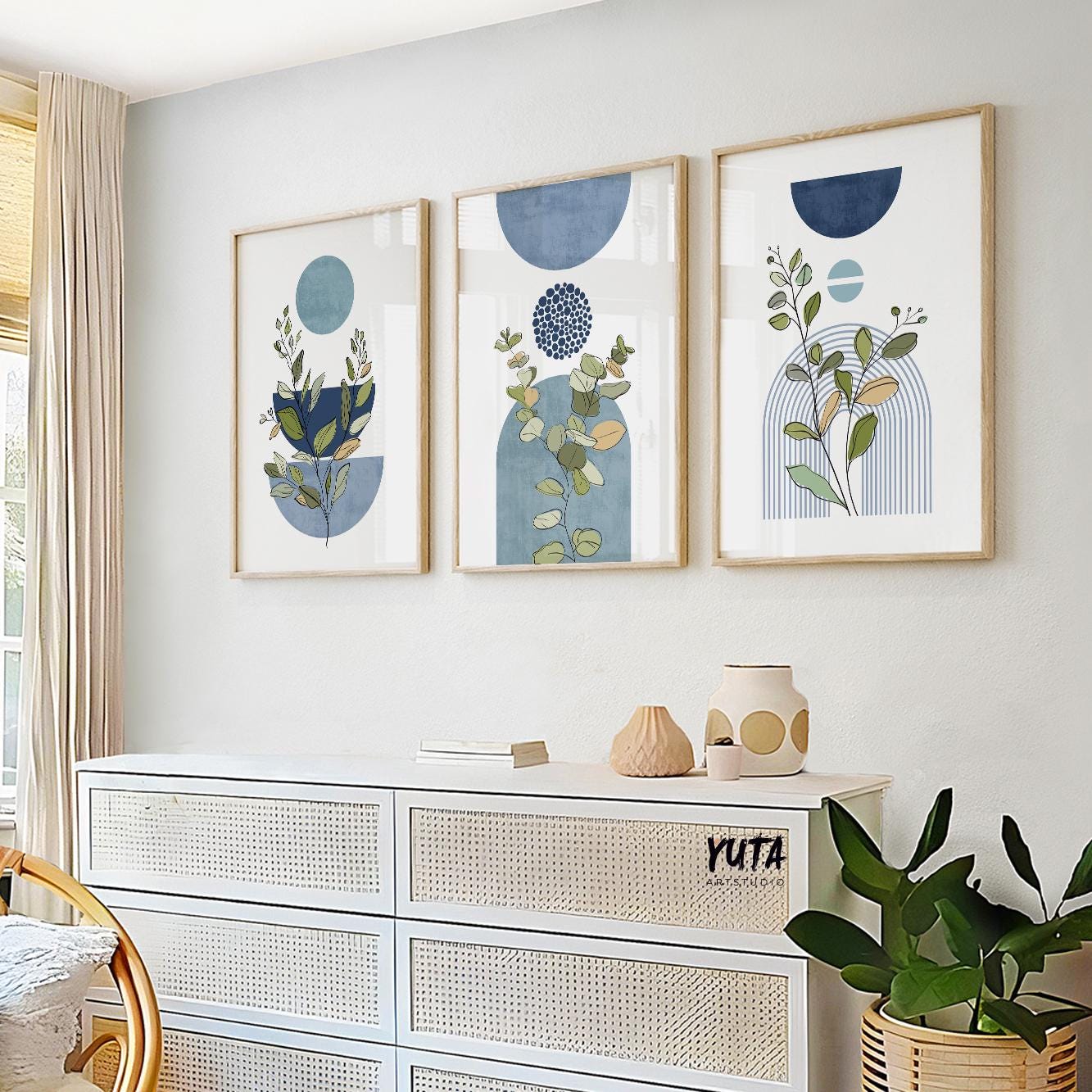 Trio of blue geometric botanical art prints in natural wood frames above a sideboard
