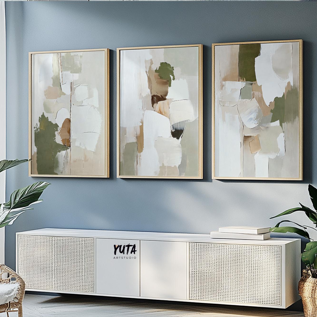 Trio of framed abstract olive green and beige prints styled over a white sideboard with books and plants
