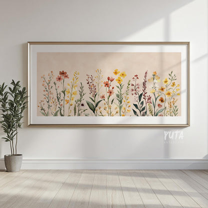 Framed neutral floral art print above light wood floors, styled with a potted plant.