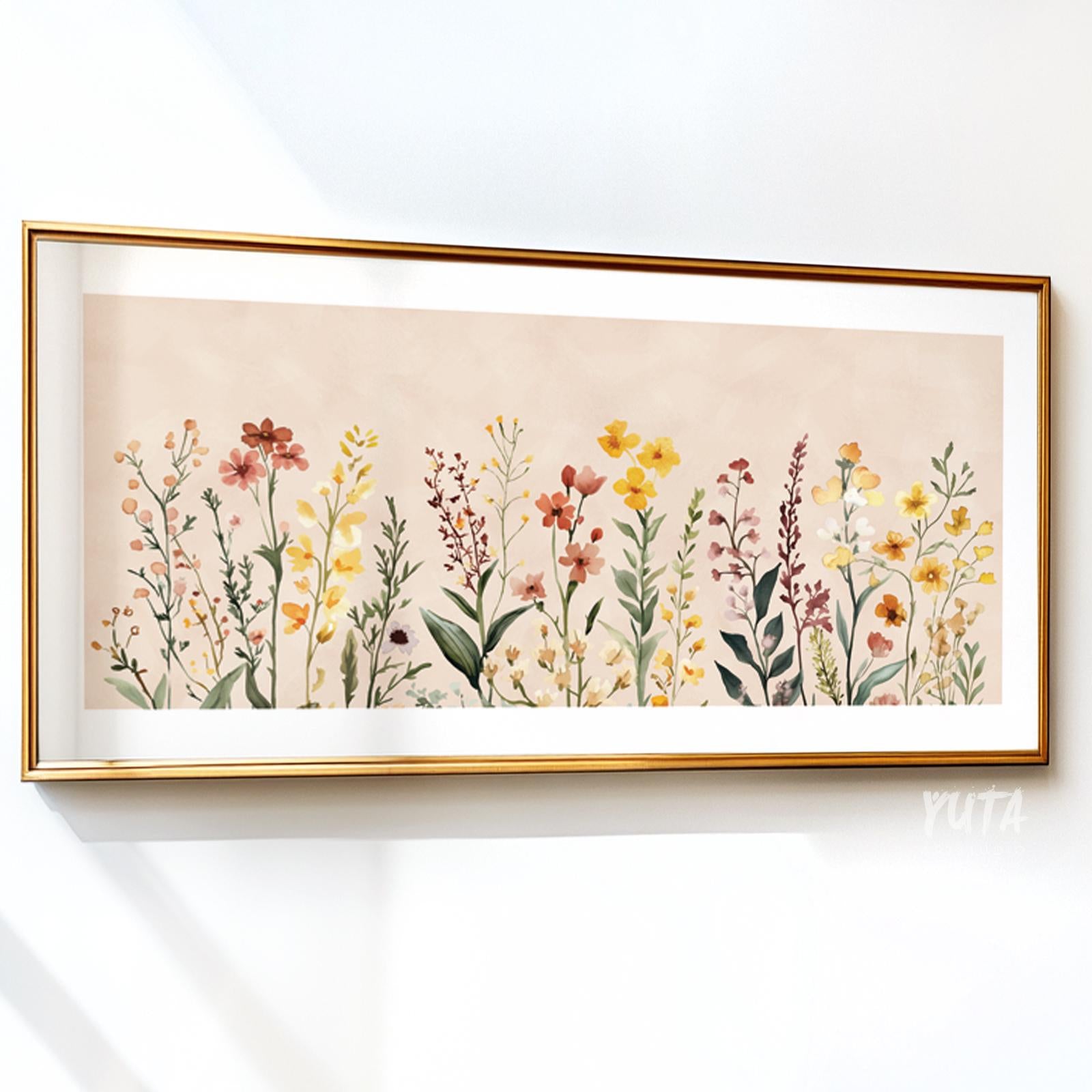 Neutral floral illustration with wildflowers in soft colors, framed in gold on a white wall