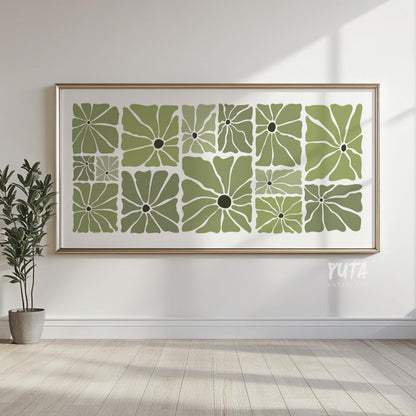 Olive green retro floral artwork in a thin gold frame displayed on a sunlit wall.