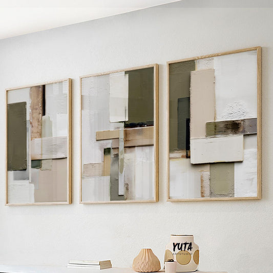 Olive and beige abstract geometric triptych in light wood frames arranged above a white shelf