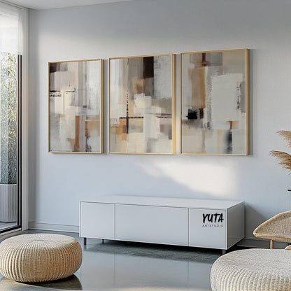 Set of three framed neutral abstract paintings hung above a modern white sofa bench