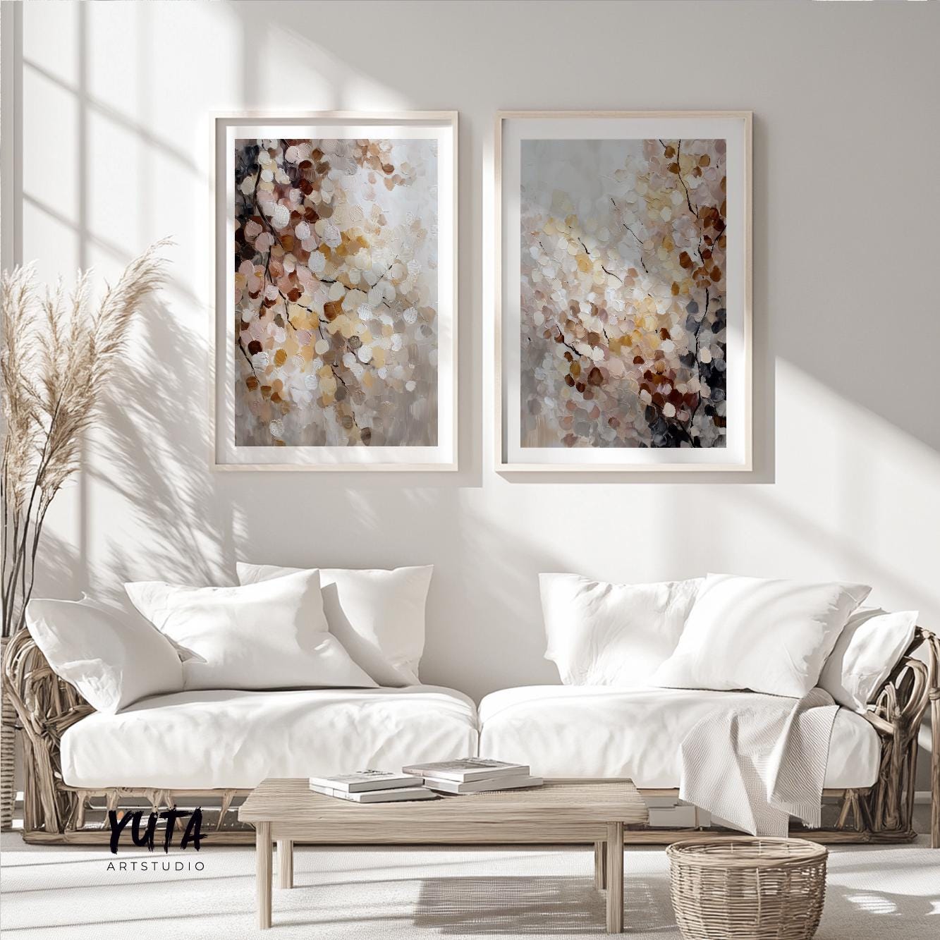 Two abstract botanical prints in light wood frames above a neutral sofa with pampas grass