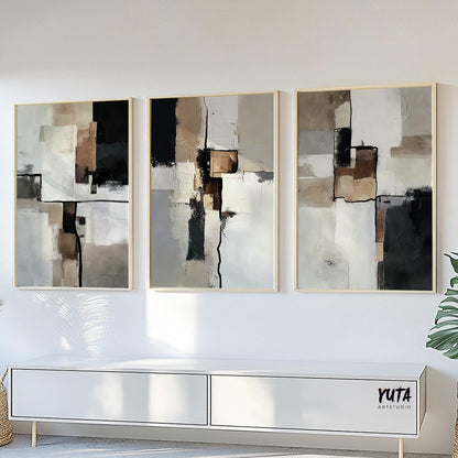 Three abstract paintings with beige, black, and brown brushwork framed above ceramics and greenery
