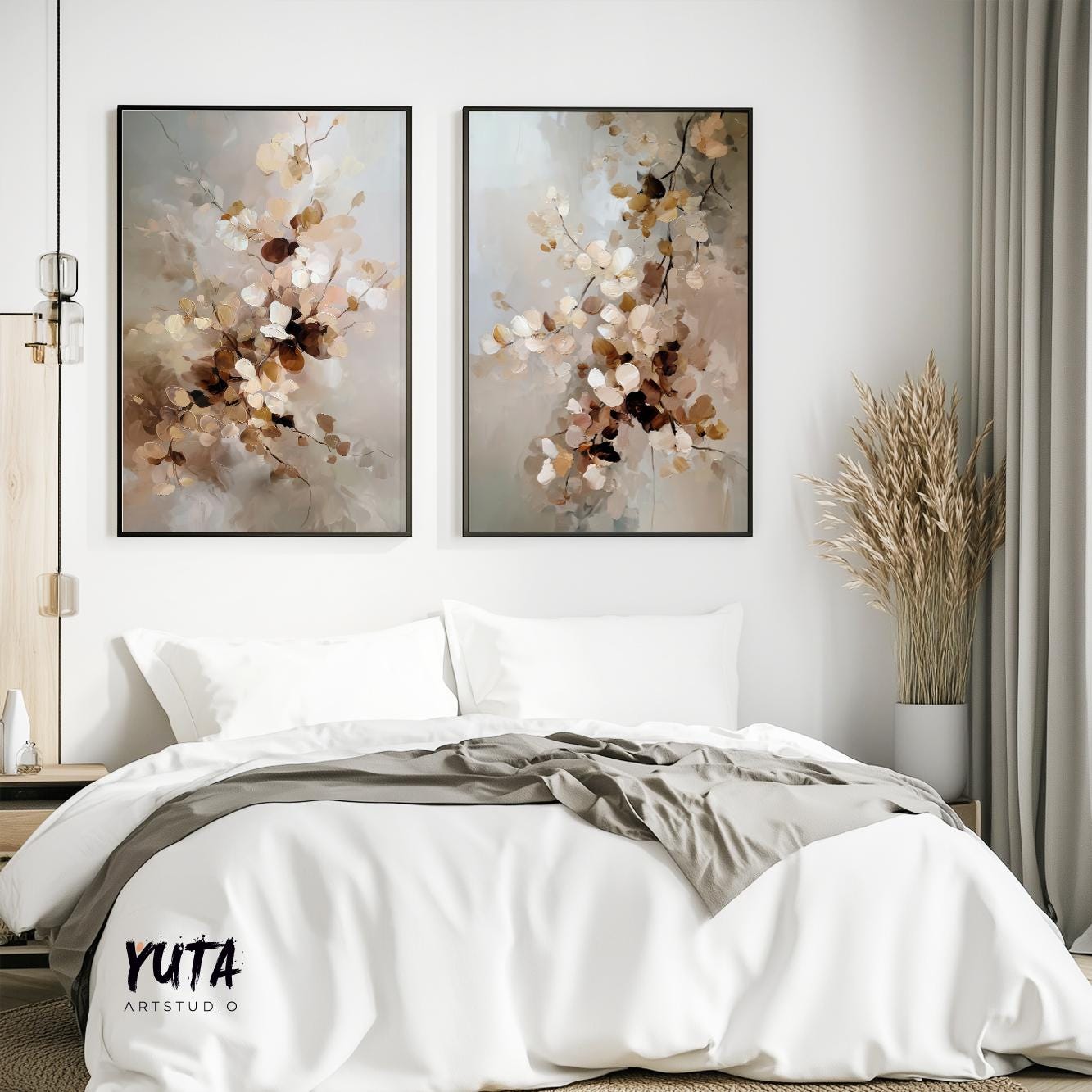 Two framed neutral botanical prints above a bed, styled with dried grasses and books.