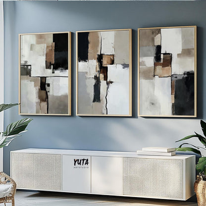 Three neutral-toned abstract prints in light wood frames shown above a low cabinet for scale