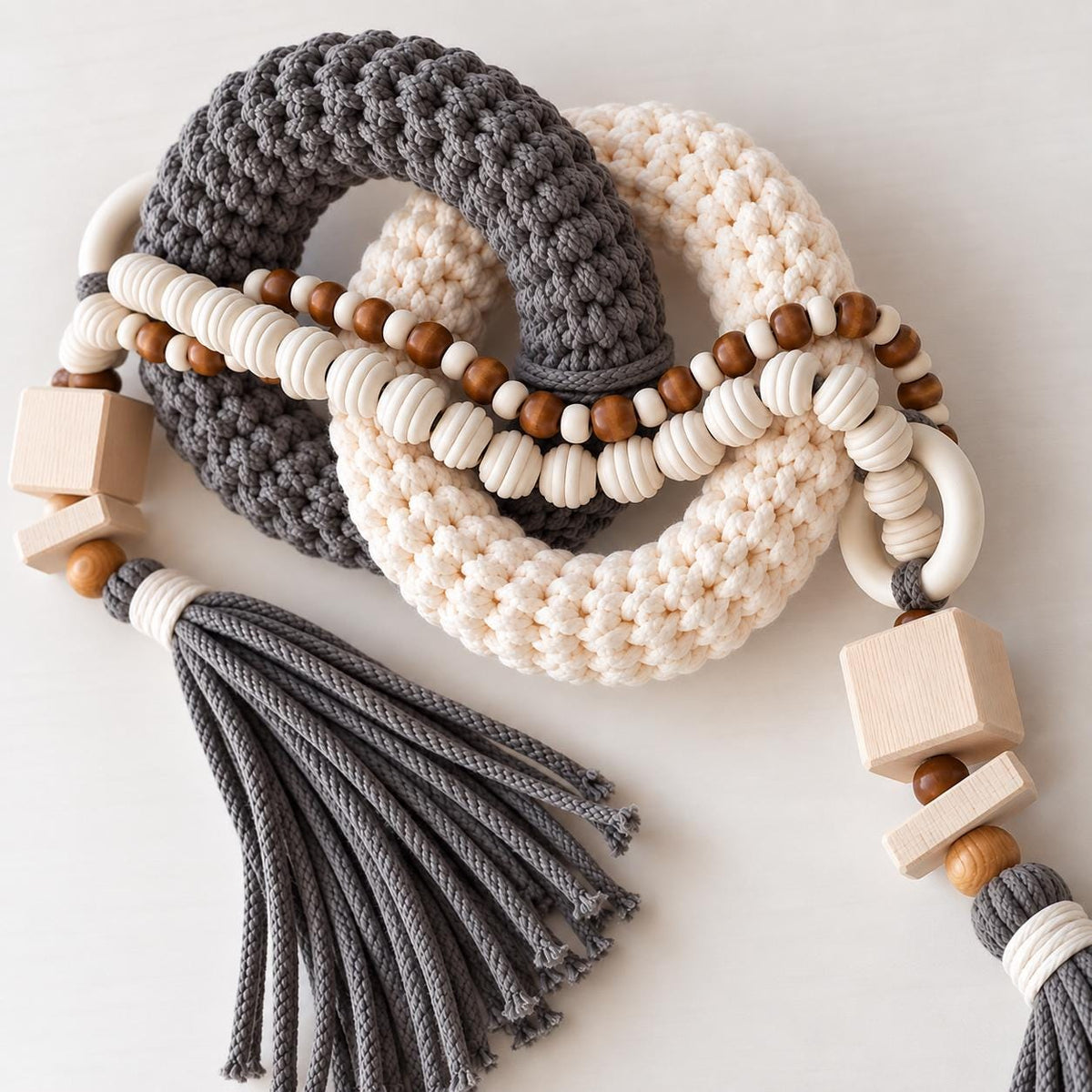 Close up of gray and cream handmade table decor with woven rings wooden beads and tassel