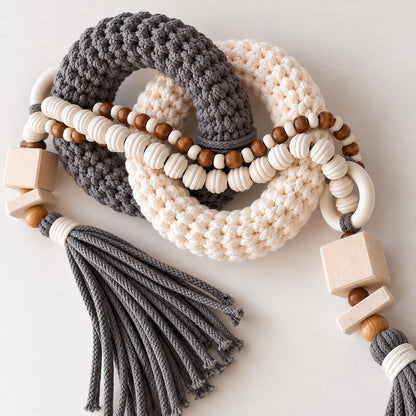 Close up of gray and cream handmade table decor with woven rings wooden beads and tassel