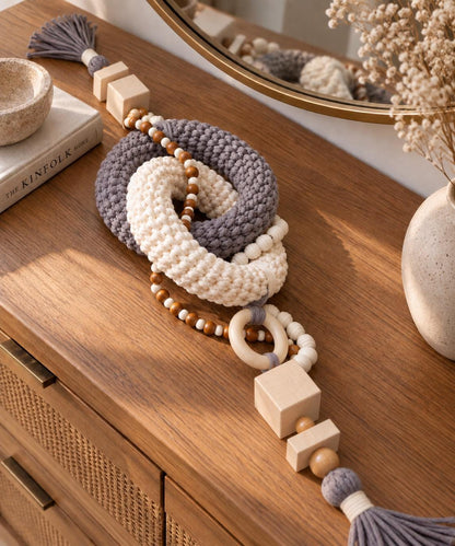 Gray and cream handmade shelf decor object with wooden beads and tassels on a coffee table
