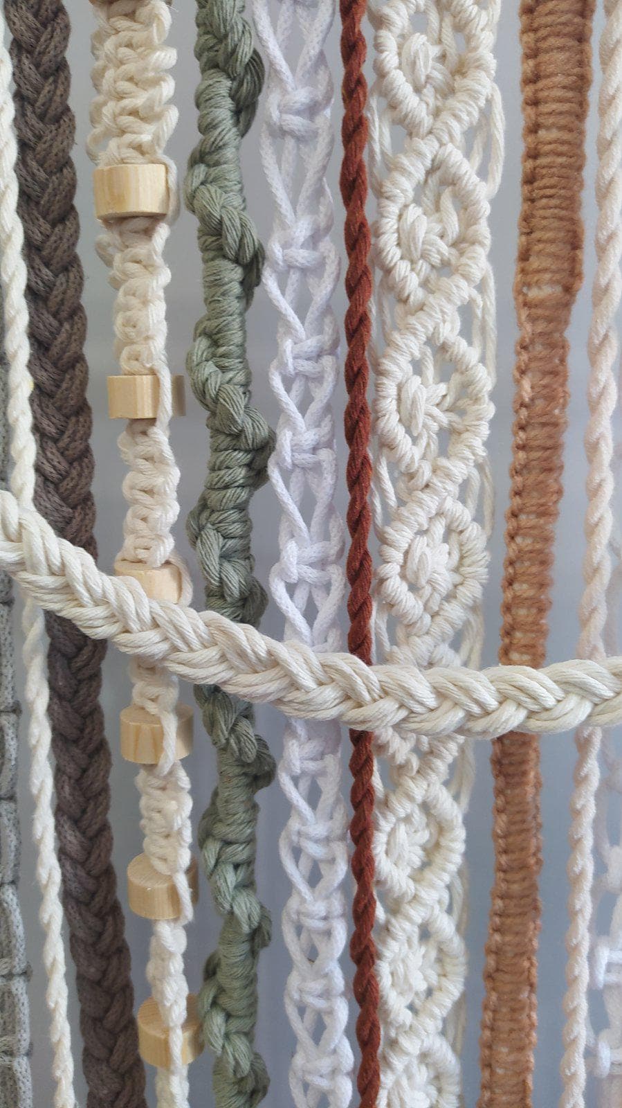 Close up of handmade macrame wall art with wooden beads braided cords and knots