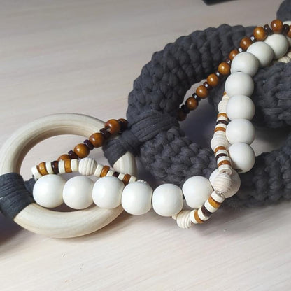 Close up of handmade decorative chain showing textured gray fiber links and wooden beads