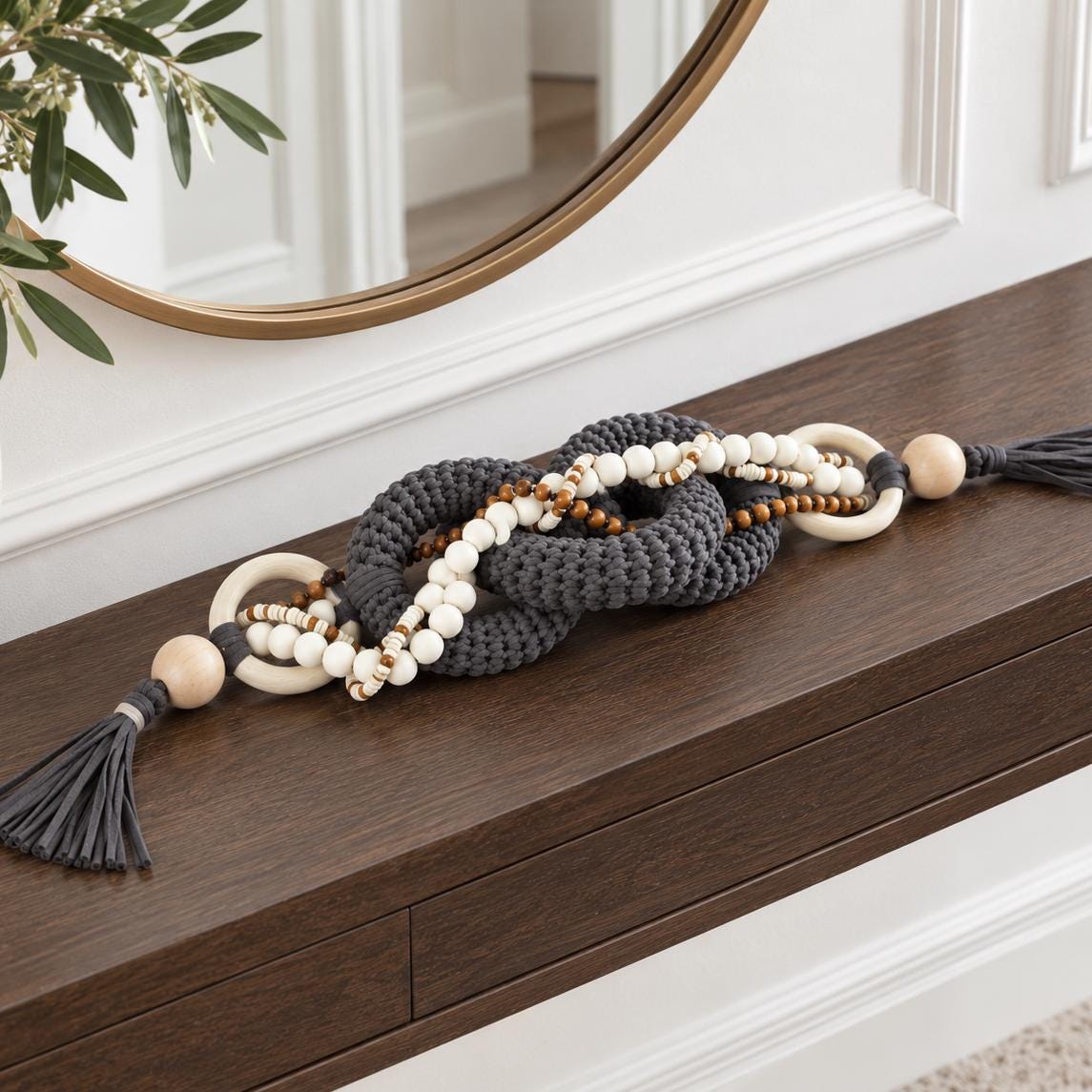 Charcoal gray decorative chain with wooden rings, white beads and tassels styled on a console table