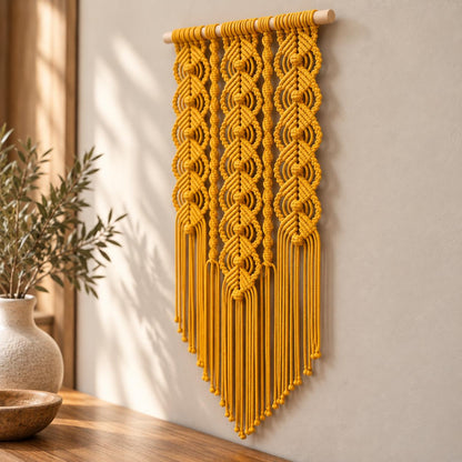 Vertical yellow wall hanging suspended from a natural wooden dowel