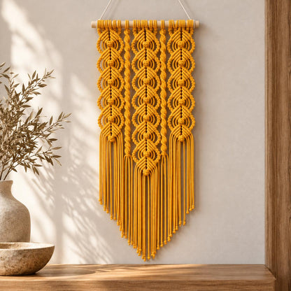 Decorative yellow macrame wall art styled against a warm white wall