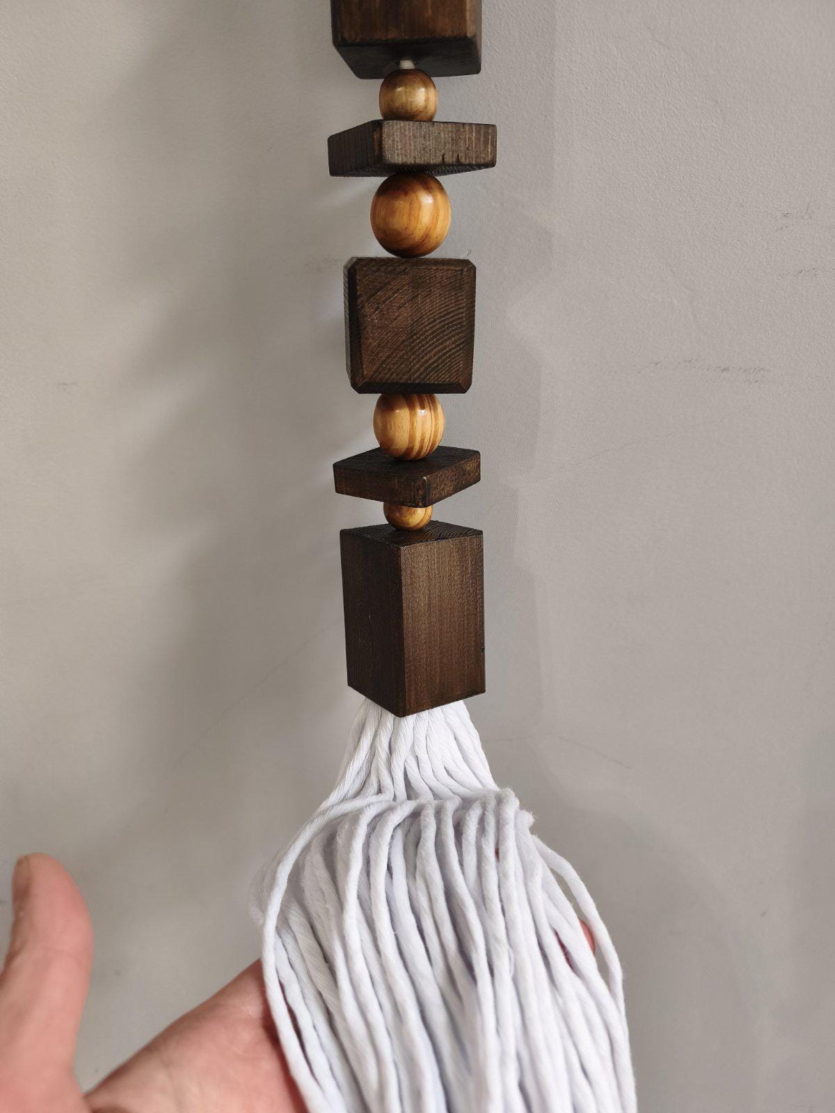 Close up of handmade wood bead wall hanging with long white cotton tassel