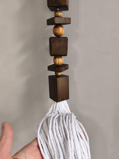 Close up of handmade wood bead wall hanging with long white cotton tassel