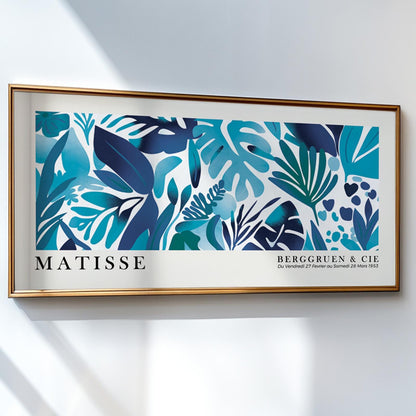 Framed Matisse-inspired blue tropical leaves print hanging above a stack of books.