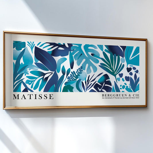 Framed Matisse-inspired blue tropical leaves print hanging above a stack of books.