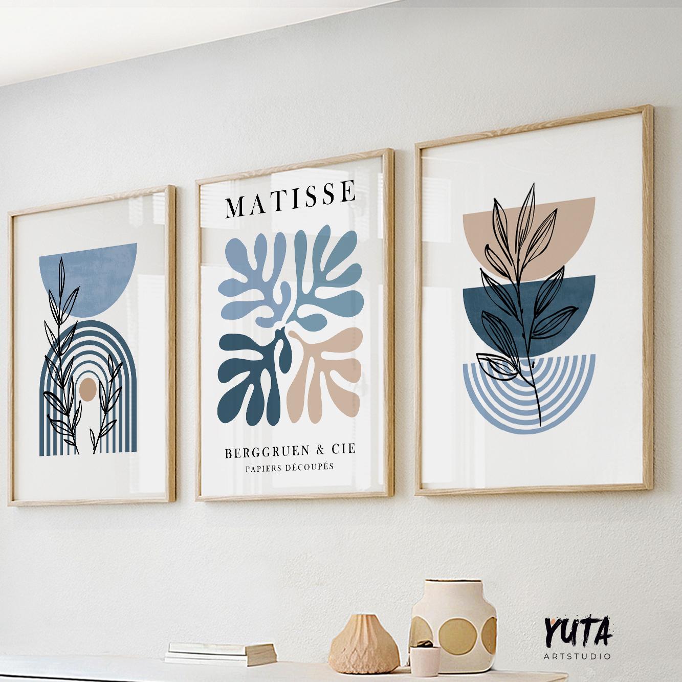 Trio of mid-century Matisse prints in light wood frames above books and ceramic vases