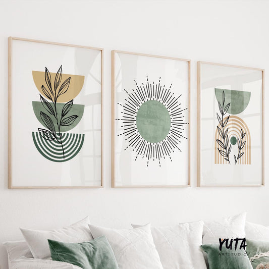 Trio of sage green boho prints in light wood frames hung above a white sofa
