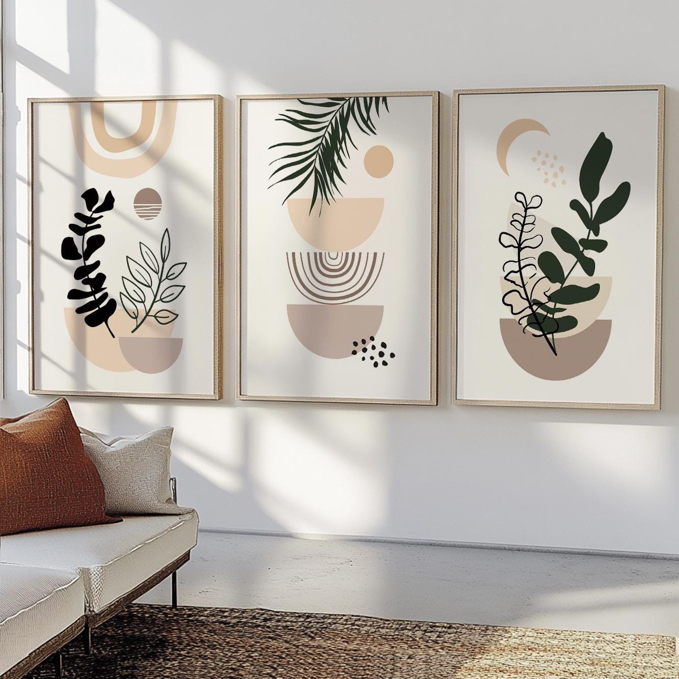 Three abstract botanical boho prints in natural frames displayed above a cream sofa.