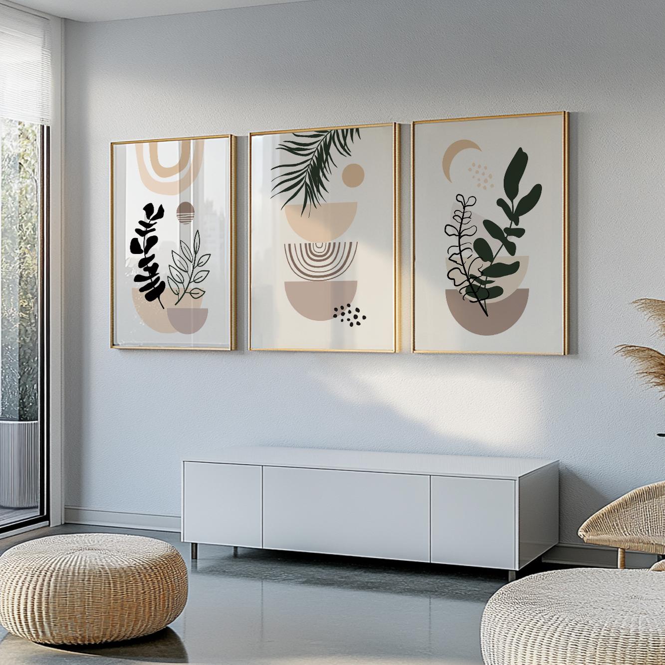 Three abstract botanical prints in gold frames hung above a white cabinet in daylight