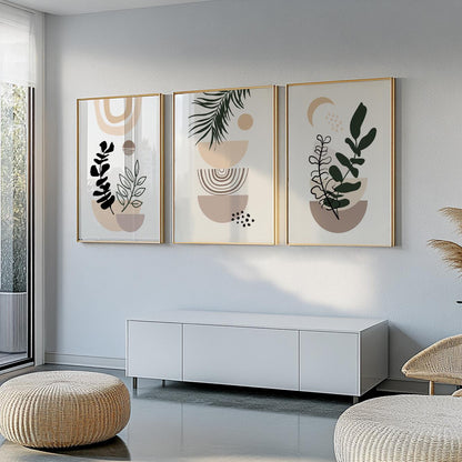 Three abstract botanical prints in gold frames hung above a white cabinet in daylight