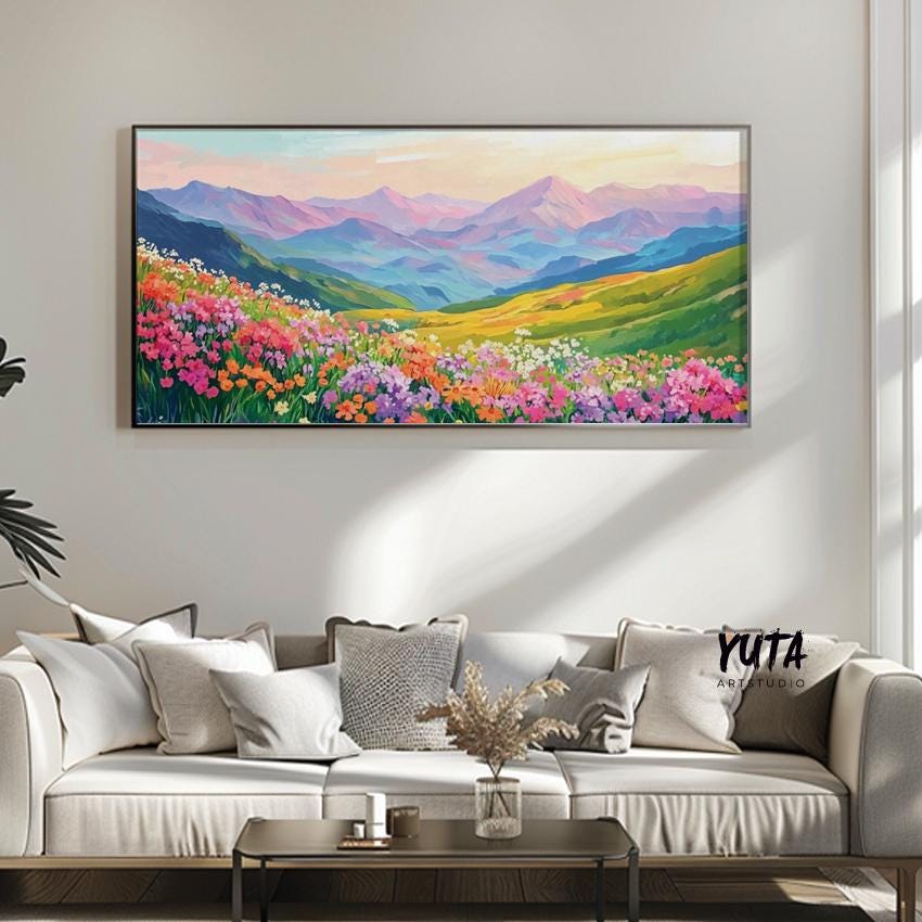 Vibrant mountain landscape artwork in a modern frame above a neutral sofa with plant decor.