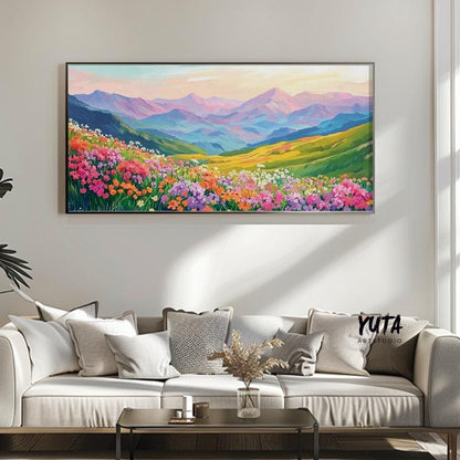 Vibrant mountain landscape artwork in a modern frame above a neutral sofa with plant decor.
