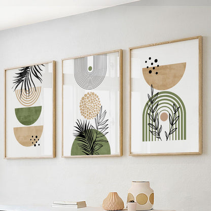 Abstract botanical print trio in natural wood frames arranged above ceramic vases and books