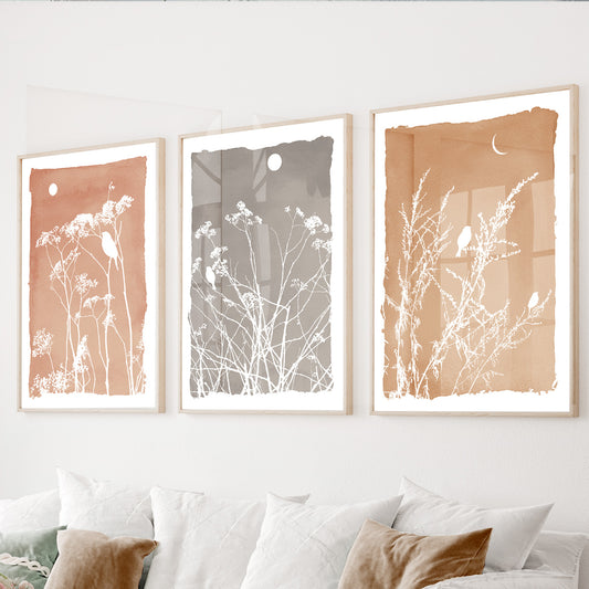 Neutral botanical wall art set of 3 featuring wildflowers and perched birds on textured terracotta and gray backgrounds