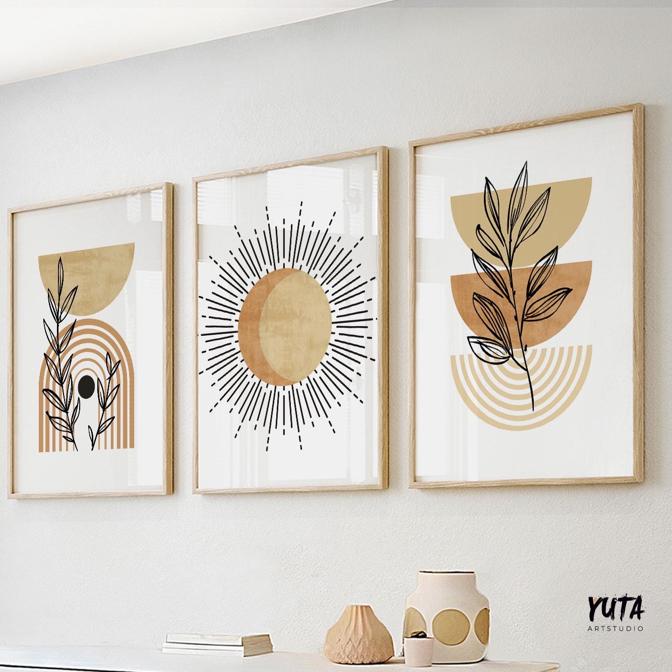 Trio of terracotta boho abstract prints in wood frames above ceramics and stacked books